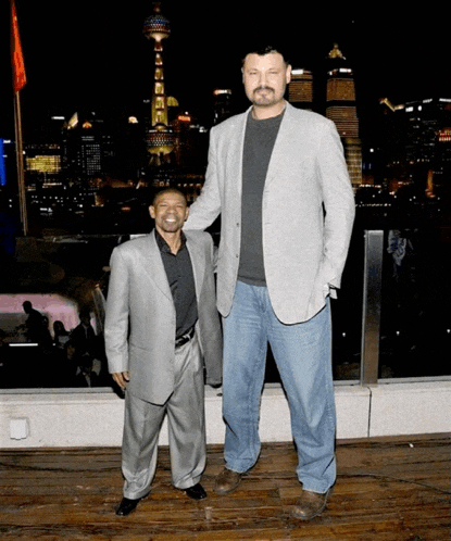 two men standing next to each other in front of a city skyline at night