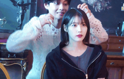 a man combs a woman 's hair while she looks at the camera