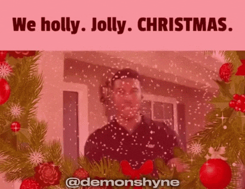 a man standing in front of a christmas tree with the words we holly jolly christmas above him