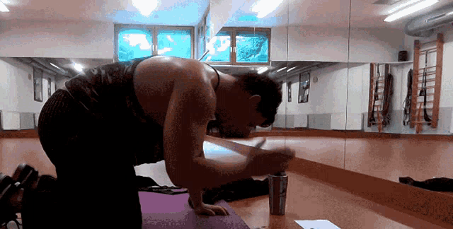 a man sits on a yoga mat in front of a large mirror