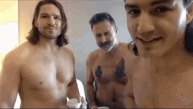 three shirtless men are standing next to each other and smiling .