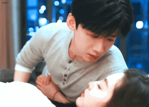 a man and a woman are laying on a bed and the man is holding the woman 's hand