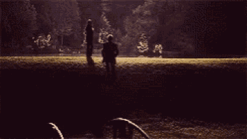 a man and a woman are standing next to each other on a grassy field at night .