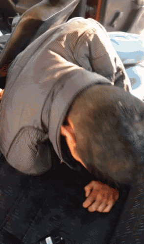 a man laying on the back seat of a car with his head down