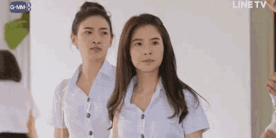 two women in white shirts are standing next to each other .