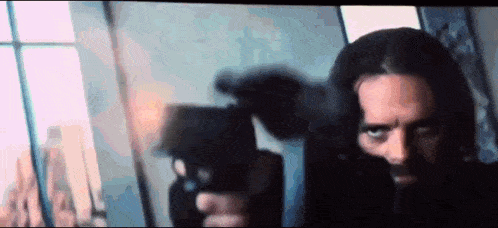 a man with long hair and a beard is holding a gun .