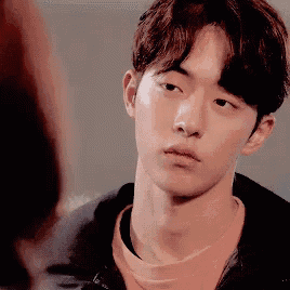 a young man wearing a pink shirt and a black jacket is looking at another person .