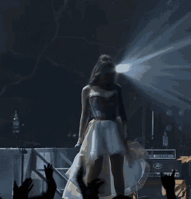 a woman in a white and gold dress is singing into a microphone on stage
