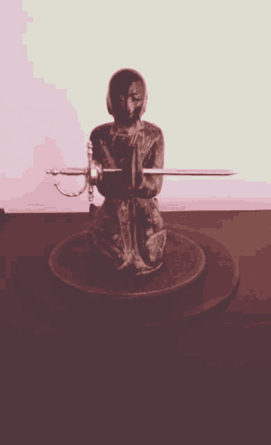 a statue of a man holding a sword with the letter a on it