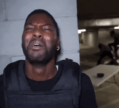 a man wearing a black vest is making a funny face with his eyes closed