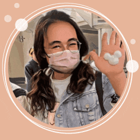 a woman wearing a mask and glasses holds up a mickey mouse shaped object