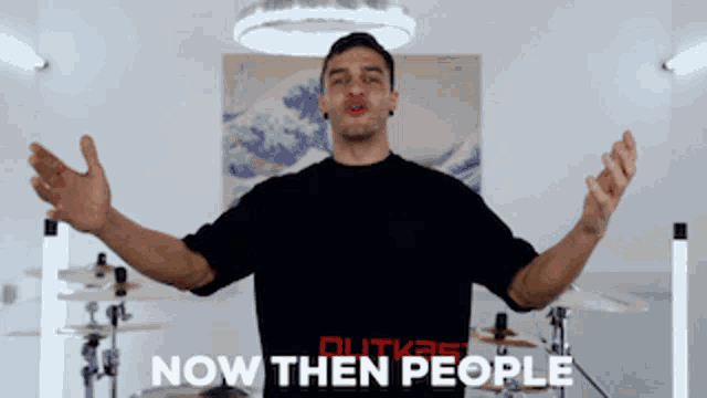 a man with his arms outstretched is wearing a black shirt that says now then people on it