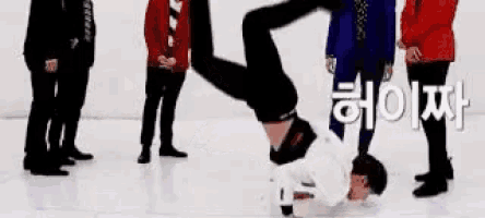 a man is doing a handstand on a ice rink while a group of people watch .