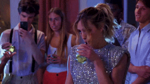 a woman in a sequined top drinks from a glass