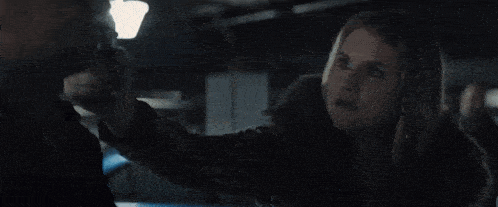 a woman is holding a gun to her head in a dark room