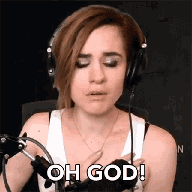a woman wearing headphones and a white tank top is talking into a microphone and saying `` oh god '' .