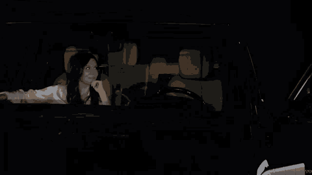 a woman sitting in a car with a man sleeping in the back seat