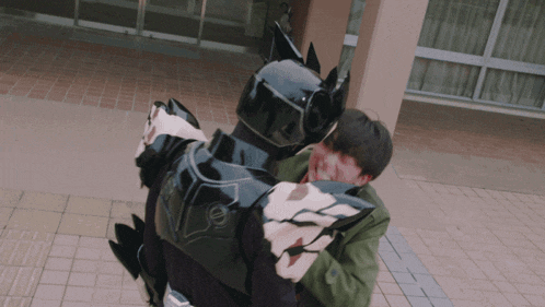 a man in a green jacket is hugging a black robot with the number 8 on it