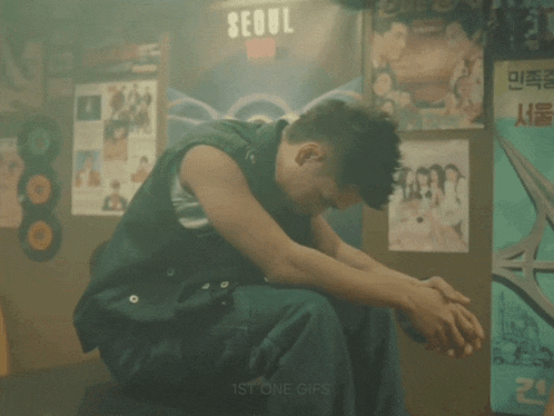 a man sits in front of a sign that says " seoul "