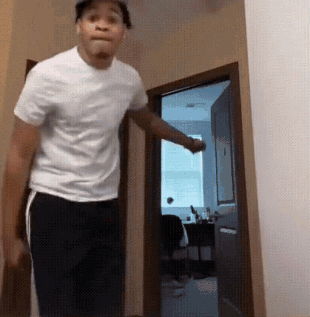 a man in a white shirt is standing in a hallway