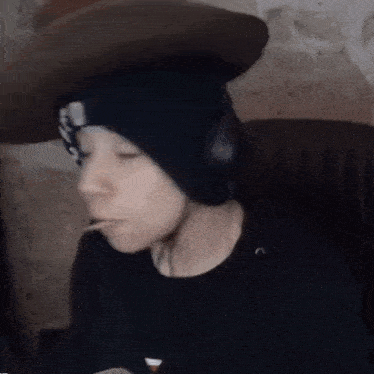 a person wearing a hat and headphones is sitting in a chair with a straw in their mouth .