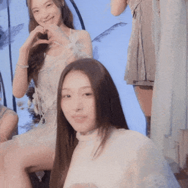 a woman in a white dress is making a heart with her hands