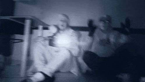 a blurry photo of a person sitting under a table holding a flashlight .