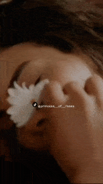a close up of a woman holding a flower in front of her face .