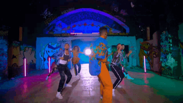 a group of people are dancing in front of a wall that says ' graffiti '