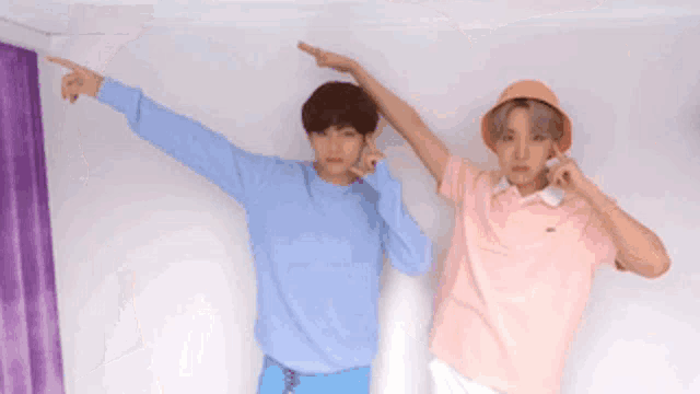 two young men are standing next to each other in a room .