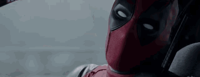 a close up of a deadpool sitting in a car looking out the window .