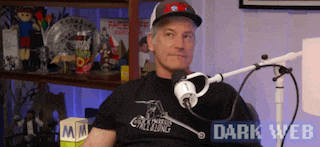 a man in a black shirt is sitting in front of a microphone with dark web written on the bottom