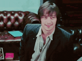 a man in a suit sits in front of a couch