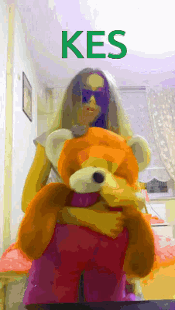 a woman is holding a teddy bear with the word kes on the top