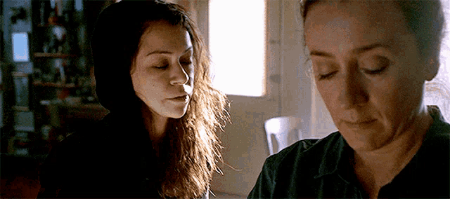 two women are standing next to each other in a dark room .