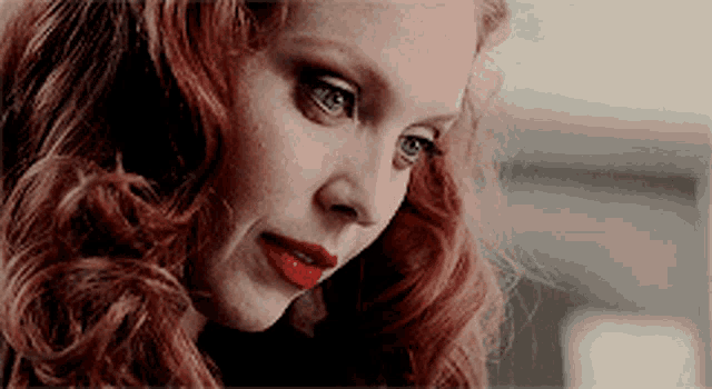 a close up of a woman 's face with red hair and red lips