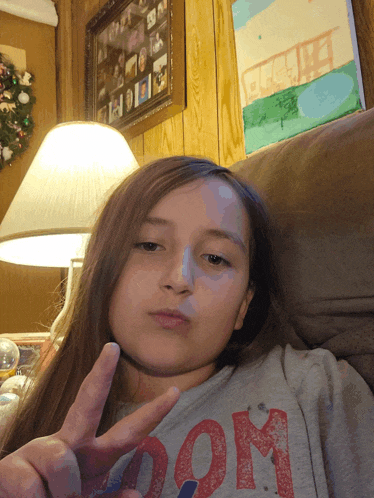 a girl giving a peace sign wearing a shirt that says " mom "