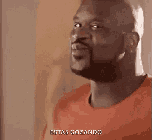 a man with a beard is wearing an orange shirt and says estas gozando