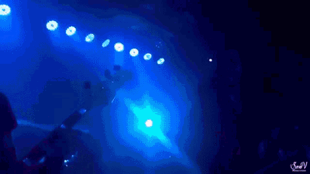 a man playing a guitar and a woman playing drums on a stage in front of a sign that says sven v