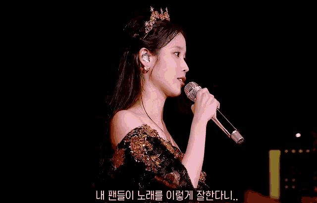 a woman singing into a microphone with a crown on her head