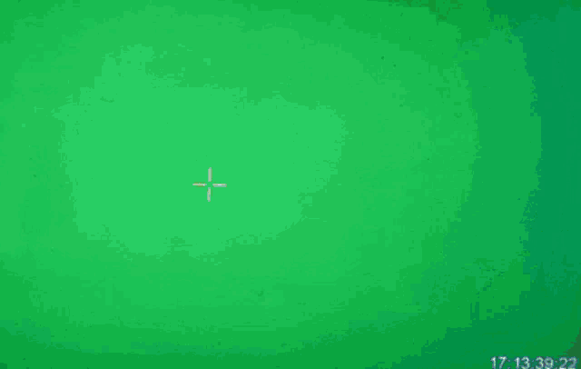 a man with a bun on his head is looking up at a green screen with a cross on it