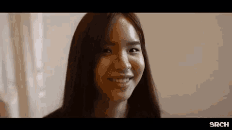 a close up of a woman 's face with long hair smiling .