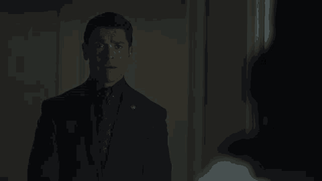 a man in a suit and tie is standing in the dark
