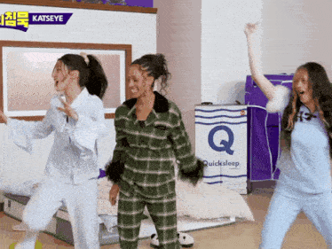 three women in pajamas are dancing in front of a quicksleep mattress