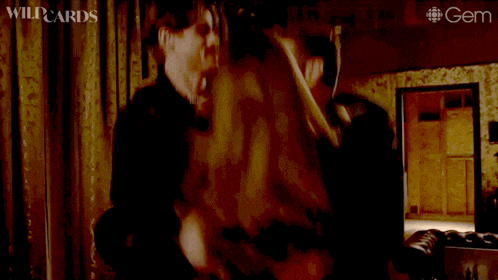 a man and woman hugging in a dark room with wildcards written on the bottom left