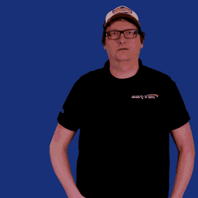 a man wearing a black shirt and a red hat holds up his hands in front of a blue background