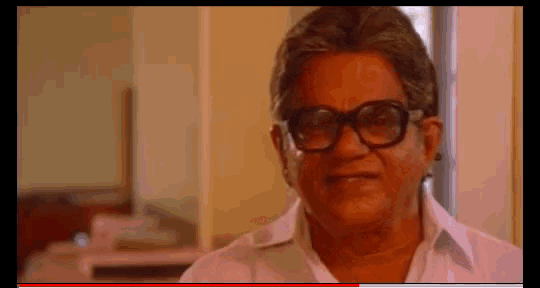 a man wearing glasses and a white shirt smiles