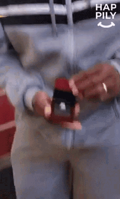 a man is holding a box with a ring in it and the words hap pily on the bottom