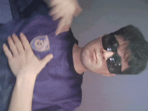 a man wearing sunglasses and a purple shirt that says cs
