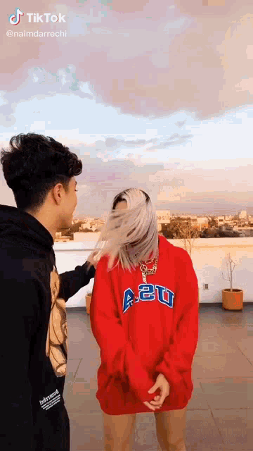 a boy and a girl are standing next to each other on a rooftop .